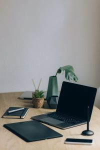 Bureau en bois avec un ordinateur portable, un carnet et une plante verte