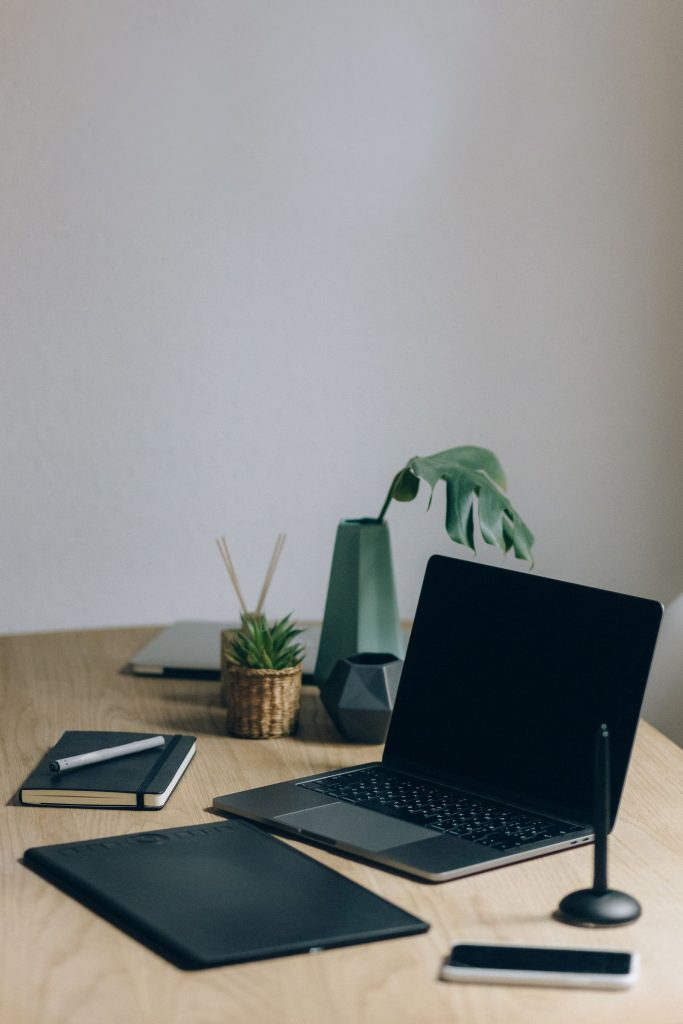 Bureau en bois avec un ordinateur portable, un carnet et une plante verte