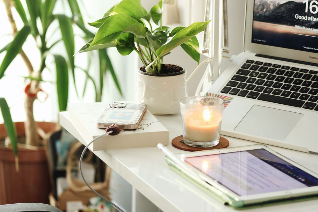 Bureau lumineux avec un ordinateur portable, des plantes vertes et une bougie allumée